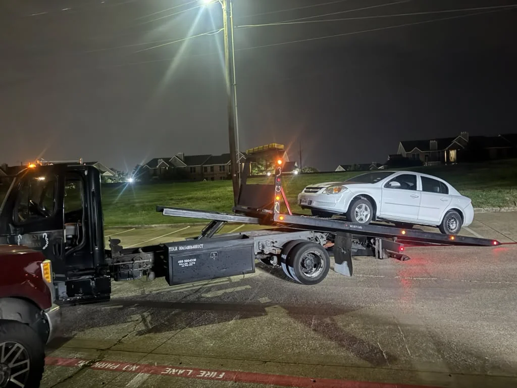 West Dallas Towing tilted rollback bed assisting motorist at night in DFW residential area